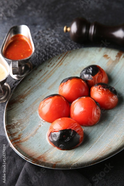 Fototapeta Grilled vegetables. Fried tomatoes with herbs on a plate, red and white sauces, ketchup, spices. Rosemary on a dark table. Turkish cuisine, dish. Vegetable garnish. Background image, copy space