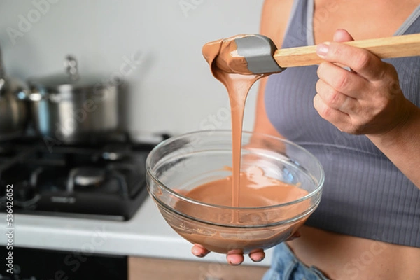 Fototapeta The process of tempering chocolate and making chocolates. Pastry chef using spatula tempering molten chocolate