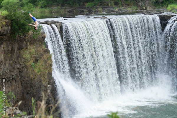 Obraz A men is diving from a cliff at Jingbo Lake falls in Heilongjiang, China. Waterfall and Mountain landscape.