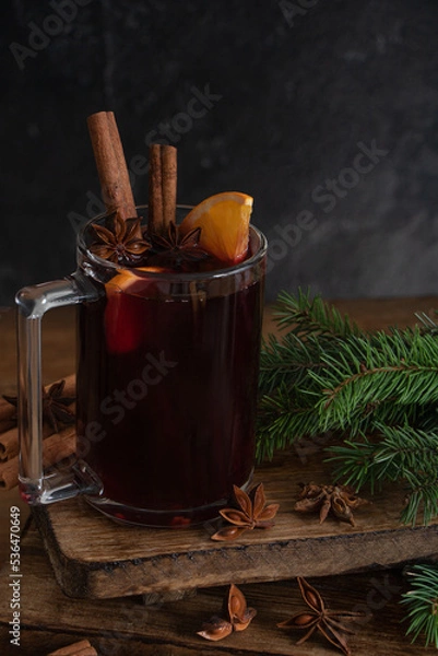 Fototapeta Mulled wine, a hot warming drink with spices, cinnamon, orange and anise on a wooden background.