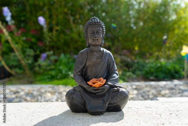 Obraz Buddha statue near house in front of garden.