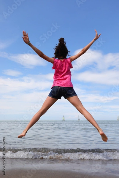 Fototapeta happy girl jumping and rejoicing for joy by the sea