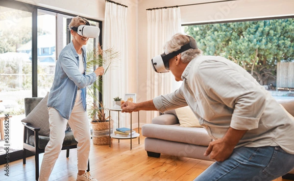 Fototapeta VR, gaming and metaverse with a senior couple playing a video game in their home for fun together. 3d, virtual reality and internet with an elderly gamer and his wife enjoying an immersive experience