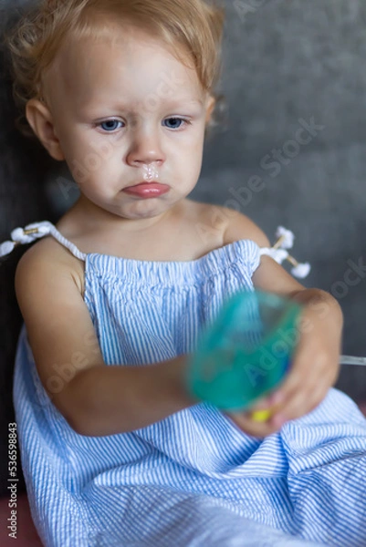 Fototapeta a child with snot holds a mask from a nebulizer in his hands.
