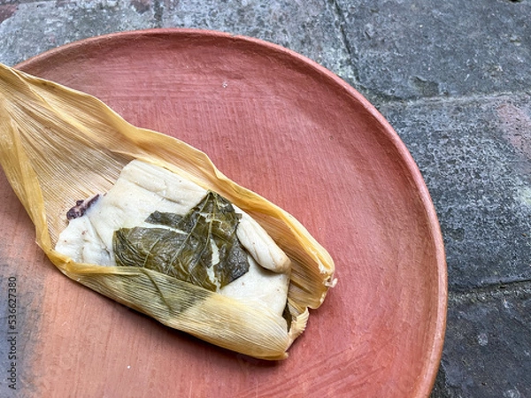 Fototapeta One Oaxacan tamale with hoja santa wrapped on the outside of the masa and filled with beans with brick background