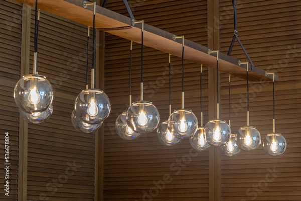 Fototapeta Globe glass pendant light Chandelier in Antique Brass Finish with wooden cladding background, selective focus