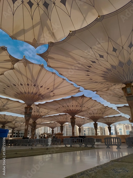 Obraz Medina, Saudi Arabia - October 07, 2022: Umbrella construction on the square of Al-Masjid An-Nabawi or Prophet Muhammed Mosque are protecting people from sun at daytime and work as lights at night