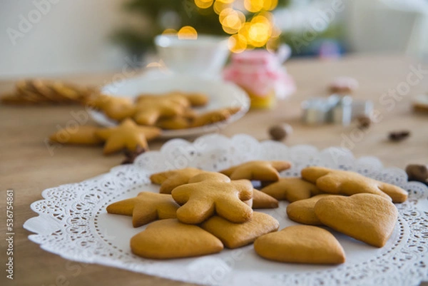 Fototapeta Plate with traditional ginger cookies in front of a Christmas tree with a herald of lights. 