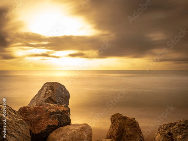 Obraz Amanecer dorado con nubes mar y rocas