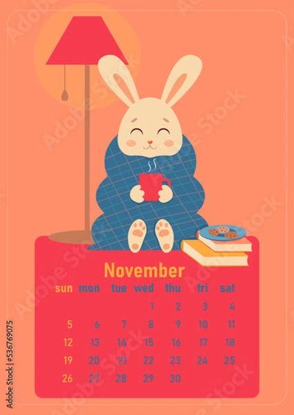 Fototapeta Calendar 2023 for november. Year of the rabbit, symbol of the new year. The week starts on Sunday. A cute rabbit is wrapped in a blanket and sits with a cup of hot drink at home with cookies and books