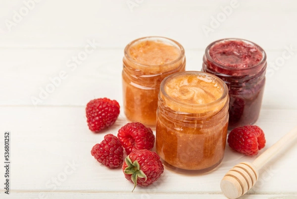 Fototapeta Honey in a glass jar. Raspberry and blueberry honey jam. Remedy for colds and respiratory diseases. Organic product of a vegetarian diet. copy space. copy space
