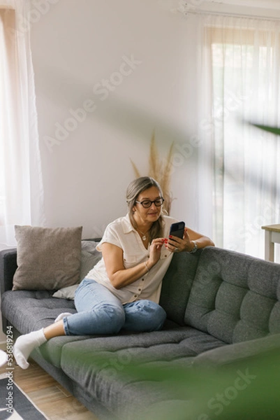 Fototapeta Woman using smartphone at home
