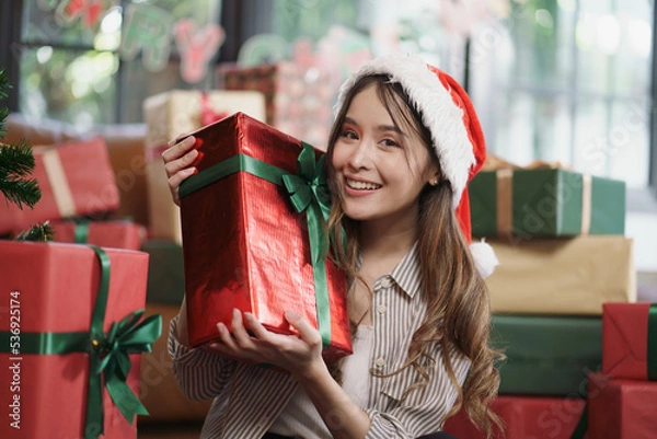 Fototapeta Asian woman with Christmas gifts box smiling to camera with a lot of present boxes in the background.