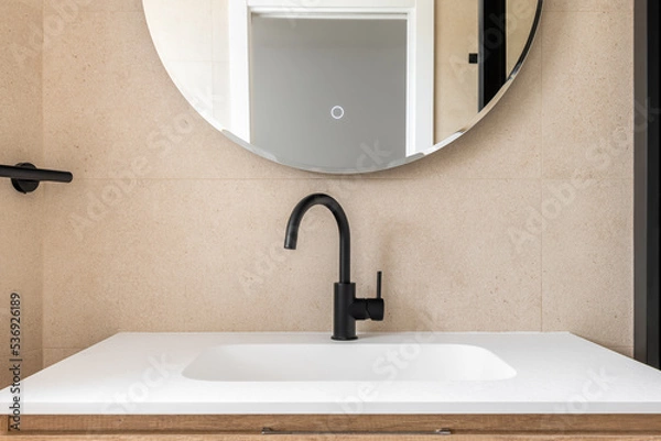 Fototapeta Close-up of stylish bathroom with black tap, round mirror and and white sink.