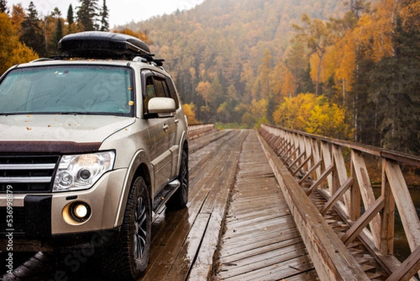 Fototapeta 4x4 car on wooden bridge in the forest in autumn