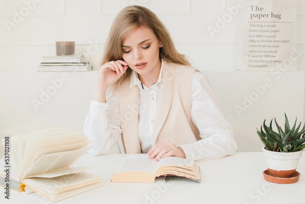 Fototapeta Beautiful business lady sitting at the table with a book