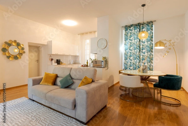 Fototapeta Modern open space in elegant apartment. There is a comfortable sofa in the foreground and the dining room behind