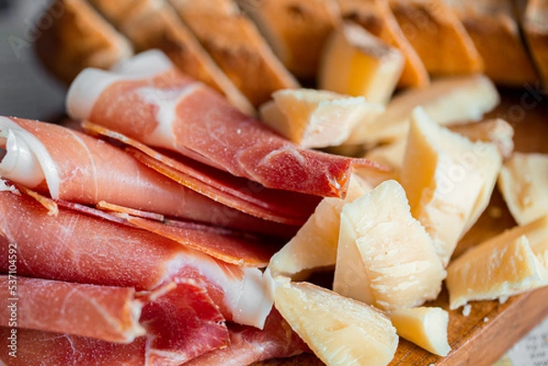 Obraz Wooden board with cheese and ham. Board with jamon and cheese. Aperitif on the board. Jamon with bruschetta and parmesan.Delicious appetizer for wine.Italian appetizer. Jamon and salami with cheese.