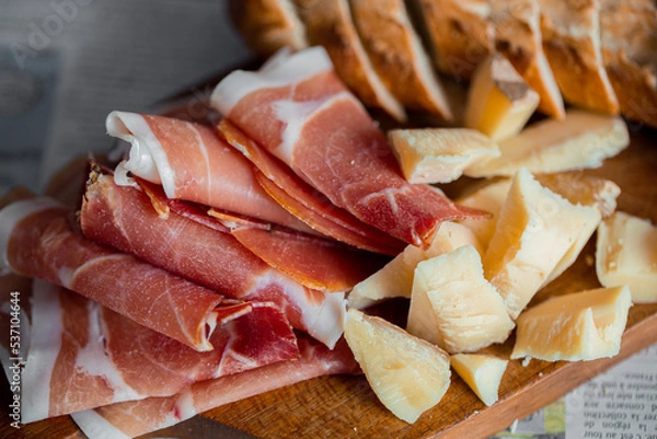 Obraz Wooden board with cheese and ham. Board with jamon and cheese. Aperitif on the board. Jamon with bruschetta and parmesan.Delicious appetizer for wine.Italian appetizer. Jamon and salami with cheese.