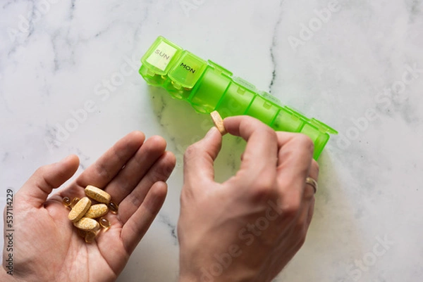 Obraz Man using a pill box organizer