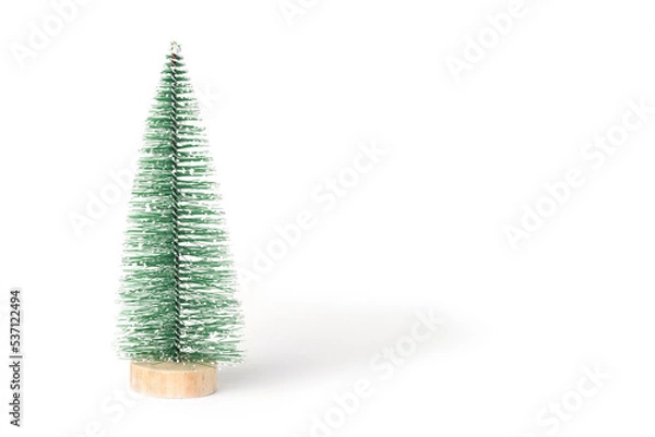 Fototapeta Green vintage bottle brush Christmas tree on a white background.  Miniature Christmas tree in the shape of a triangular brush on a wooden round stand. Front view. Copy space for holiday text.