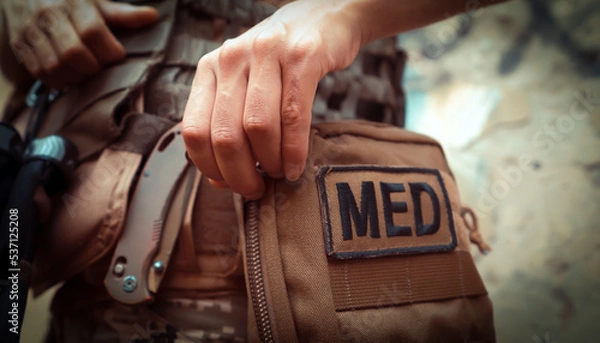 Fototapeta A soldier, a tactical medic opens a first aid kit, close-up view.