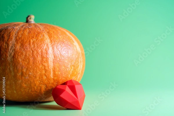 Fototapeta A red heart and pumpkin on green background,copy space