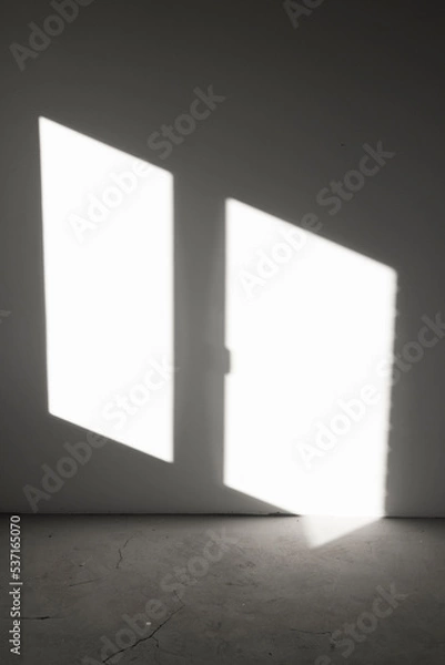 Fototapeta Shadow from the window on the gray concrete wall of an empty room. Abstract background with geometric lines in the dark.