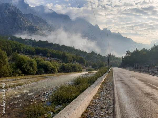 Fototapeta long road with mountain background. river and clouds. peaks of the balkan