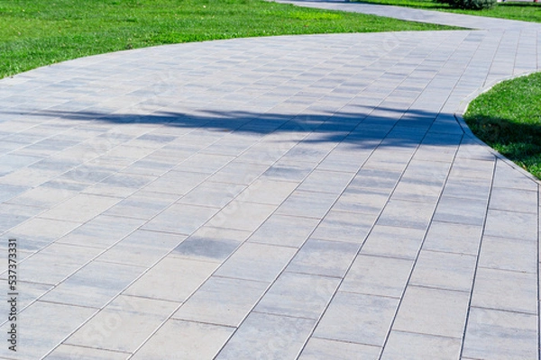 Fototapeta concrete path in the park with a lawn on the edges