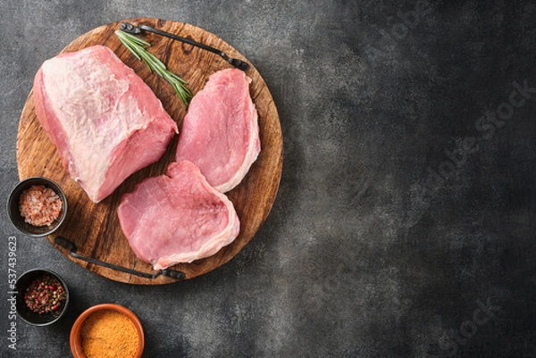 Obraz Raw pork meat on wooden board on grey background  with rosemary, salt and pepper. Pork loin. Copy space. Top view.