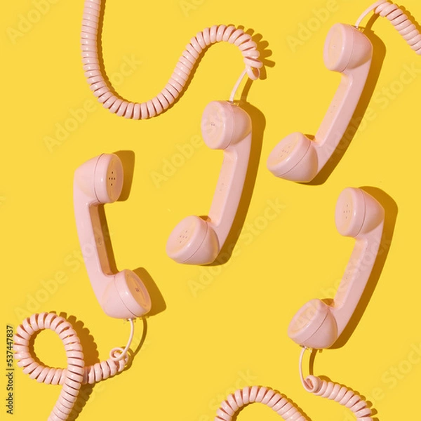 Fototapeta Creative layout with pink retro phone handsets on bright yellow background. 80s or 90s retro fashion aesthetic telephone concept. Minimal romantic handset idea. Valentines day idea.