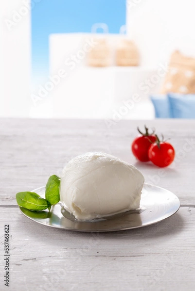 Fototapeta mozzarella with tomato and basil leaf on round silver plate, resting on white wooden table