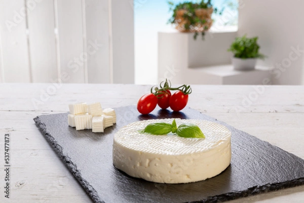 Fototapeta fresh cheese with basil leaf with tomatoes on a rectangular slate board set