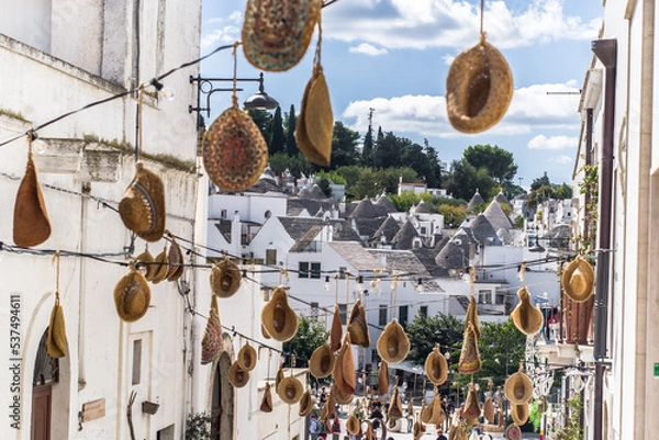 Fototapeta narrow cobblestone streets and round stone trulli houses in Arbelobello. Stone pointed roofs and brick stone whitewashed houses on a sunny day