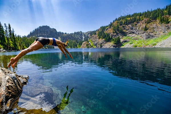 Obraz Adventurous athletic female hiker diving into an alpine lake in the Pacific Northwest.
