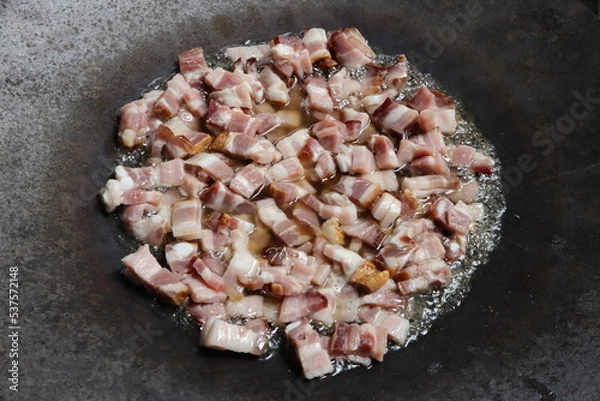 Fototapeta Sliced ​​raw bacon with a lot of fat, is fried in a large bowl. Illustration photo of uhealthy eating or not vegetarian lifestyle.