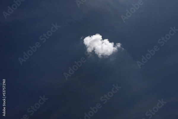 Fototapeta A single white cloud in the dark blue sky. Abstract minimalist sky landscape photo.