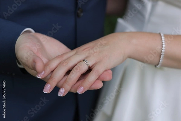 Fototapeta Newlyweds elegant couple are touching and holding each other's hands with engagement ring. Color romantic illustration photo of a happy relationship, wedding or heterosexual lifestyle.