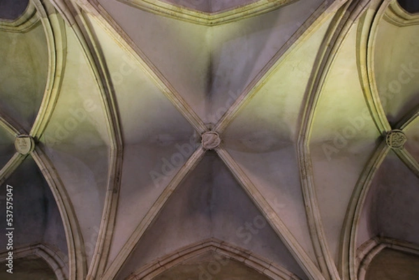Fototapeta Symmetrical arches of a gothic vault of Vajdahunyad (Hunedoara) castle in Transylvania, Romania. Color abstract interior architectural photo.