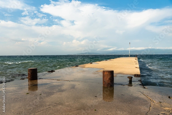 Fototapeta Sea waves break on a concrete pier.nautical concept background