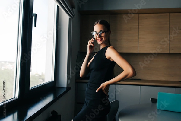 Fototapeta Серьезная очаровательная женщина, использующая смартфон во время работы