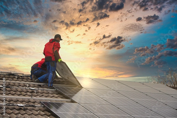 Fototapeta Installing solar photovoltaic panel system. Solar panel technician installing solar panels on roof. Alternative energy ecological concept.
