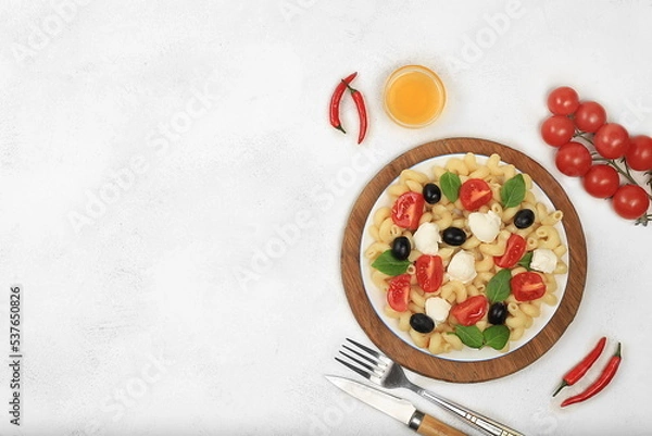 Fototapeta Italian cold pasta salad and caprese pasta, top view with space for text. Fusilli, tomatoes, mozzarella, olives and arugula salad with basil. Business card for menu, restaurant or cafe advertisement