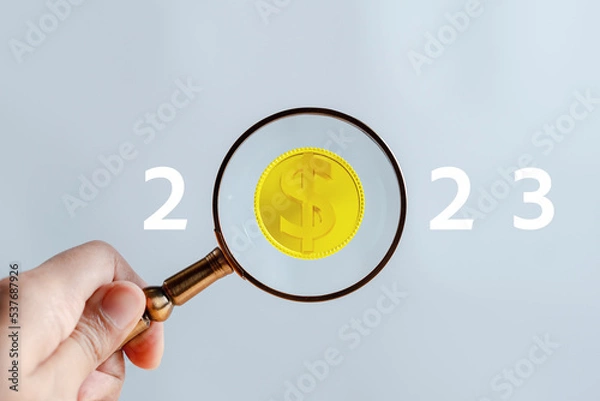 Fototapeta Investing on 2023 year concept. Magnifier focus to yellow dollar coin. planing target to next year from end 2022, New year concept.