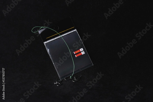 Fototapeta Fishing hook package on a black background. trap, catch on, risk. Business concept idea