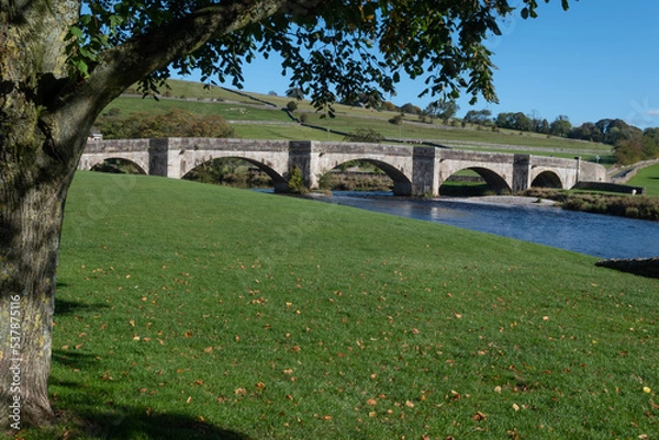 Fototapeta Burnsall bridge framed by a tree. 