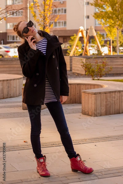 Obraz woman walking on the street in autumn and using mobile phone