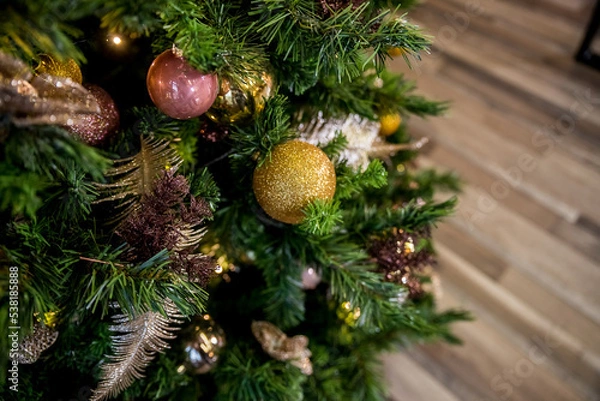 Obraz A shiny golden ball on a branch.Christmas tree decorations. New Year's decorations in pink and golden tones. Congratulations on winter holidays. Preparation for the celebration. Postcard.