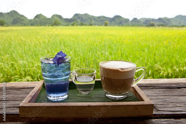 Obraz Coffee and Butterfly Pea Tea on the rice fields background. Beautiful Nature in Kanchanaburi, Thailand. Coffee with a View.